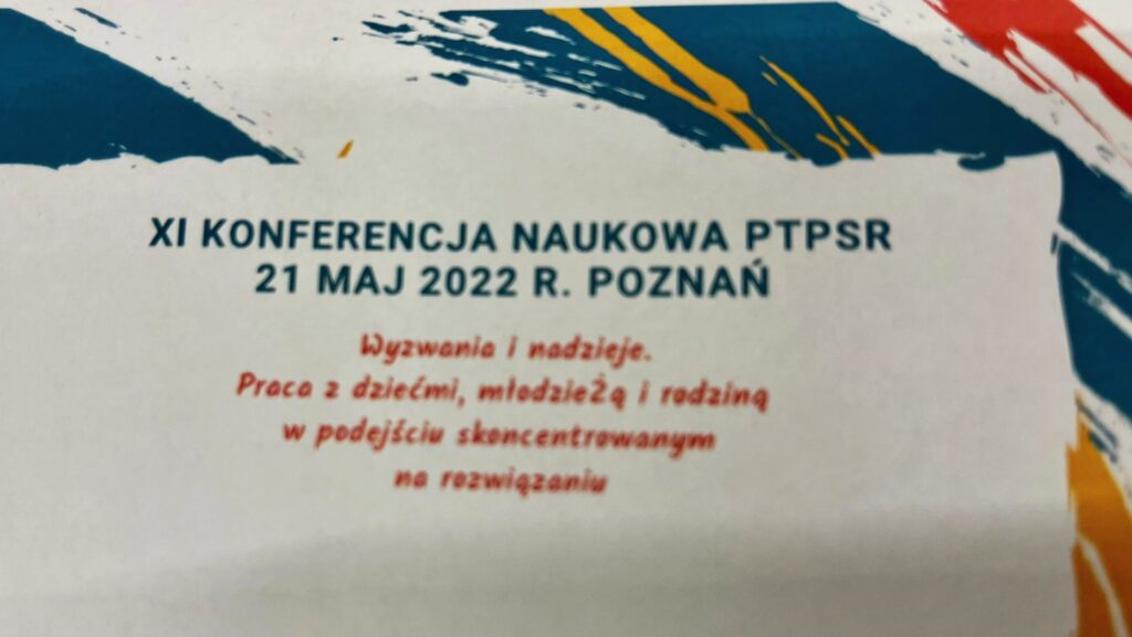 Na zdjęciu informacje o odbyciu się konferencji. Napisy czerwono niebieskie na białym tle